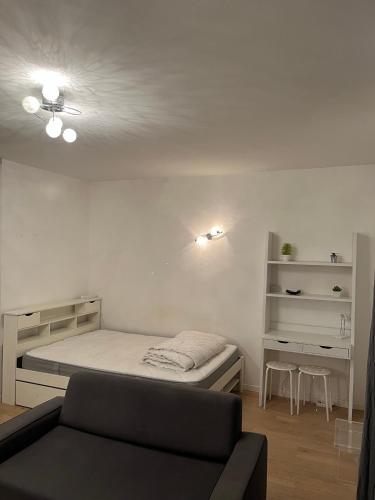 um pequeno quarto com uma cama e um sofá em Appartement proche de paris em Saint-Cloud