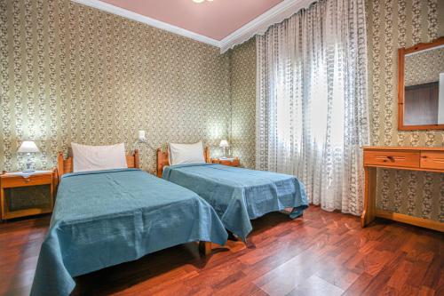 a bedroom with two beds and a dresser at SOCRATES Ethnic and traditional Home in Kalabaka