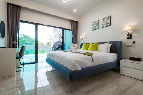 a bedroom with a blue bed and a large window at Koh Chang Luxury Pool Villas in Ko Chang