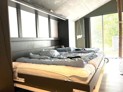 a large bed sitting in a room with windows at Hytte-vandudsigt-Hottub-hygge in Holbæk