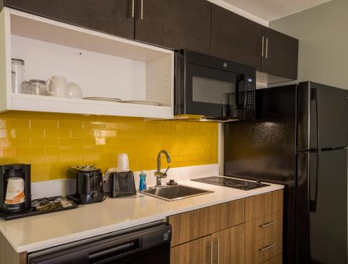 a kitchen with a sink and a black refrigerator at MainStay Suites Savannah Midtown in Savannah