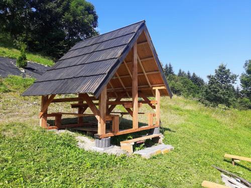 a wooden building with a roof on top of a field at Domek Na Przełęczy in Wierzbanowa