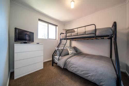 a bedroom with a bunk bed and a television at Serenity by the Sea Grange in Grange