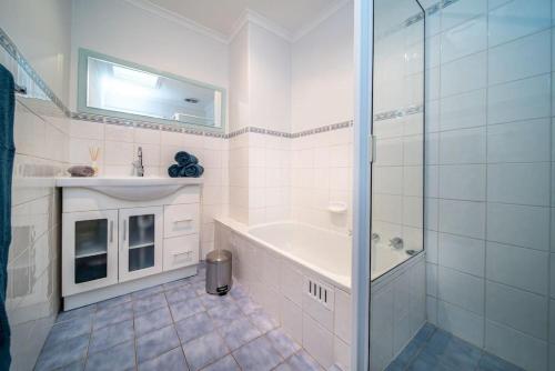 a bathroom with a shower and a tub and a sink at Serenity by the Sea Grange in Grange