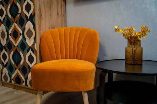 an orange chair and a table with a vase of flowers at Harmony Boutique Hotel in Drawsko Pomorskie