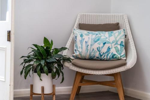 uma cadeira com uma almofada e um vaso de plantas em Summer Breeze on Cliff St em Glenelg