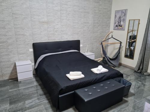 a bedroom with a black bed and a black ottoman at Appartamento del Li-Lioni di Teranga 2 in Platamona