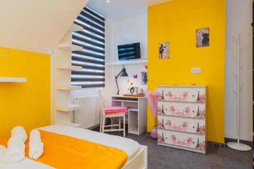 um quarto com paredes amarelas, uma secretária e uma cama em Baila Casa em Nottingham