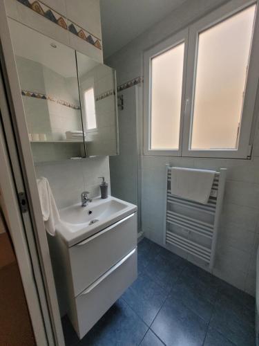 Baño blanco con lavabo y espejo en Appartement A deux pas de Montmartre, en París