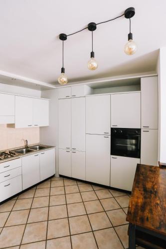 a kitchen with white cabinets and a wooden table at Flat Mazzini 6 in Alzano Lombardo