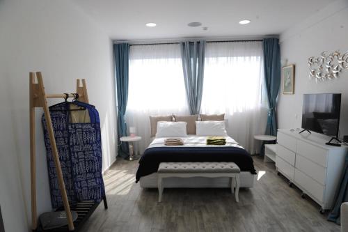 a bedroom with a bed and a tv and windows at El Angel by Ntinos in Kremasti