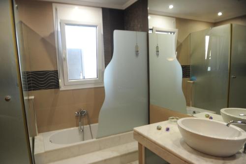 a bathroom with a sink and a tub and a mirror at El Angel by Ntinos in Kremasti