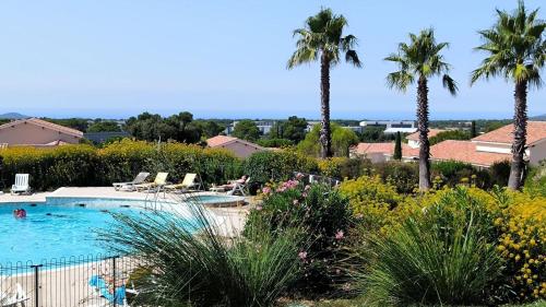 a swimming pool with palm trees and plants at Appartement 2 Pièces Le Domaine de Manon in Signes