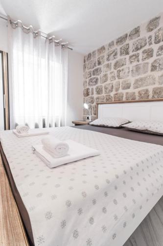 a bedroom with a large bed with a stone wall at Apartments Florian in Lopud Island