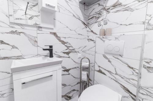 La salle de bains est pourvue de murs en marbre blanc et d'un lavabo. dans l'établissement Apartments Florian, à Lopud