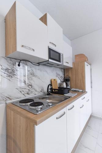a white kitchen with a stove and a microwave at Apartments Florian in Lopud Island