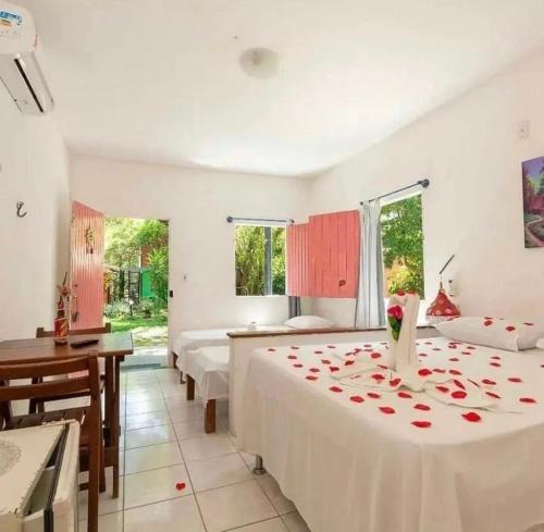 a bedroom with two beds with roses on the bed at Pousada Cajibá Imbassaí in Imbassai