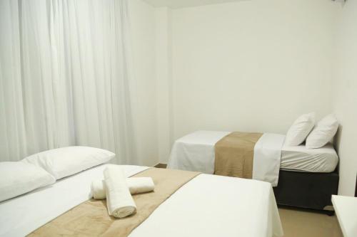 duas camas num quarto com paredes brancas e cortinas em Casa a 560 metros da Praia de Ponta Negra em Natal