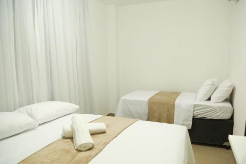 two beds in a room with white walls and curtains at Casa a 560 metros da Praia de Ponta Negra in Natal