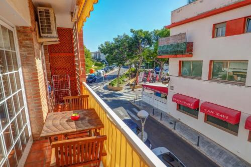 - Balcón con mesa de madera y sillas en un edificio en The Beach Apartment by Hello Homes Sitges, en Sitges