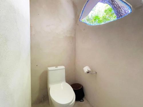 a bathroom with a toilet and a window at Ikalar in Akumal