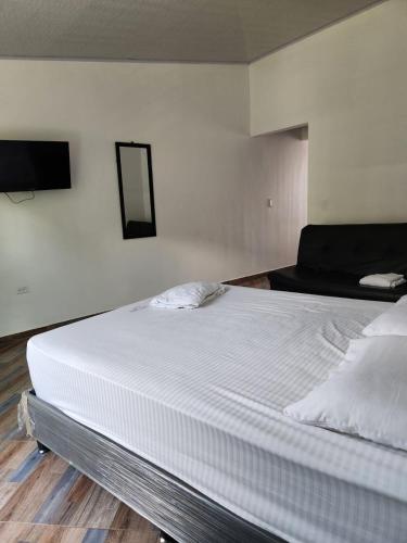 een groot wit bed in een kamer met een televisie bij aparta estudio in Cocorná