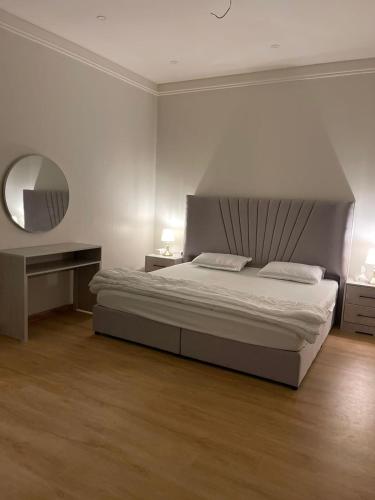 a bedroom with a large bed and a mirror at Family Furnished Apartment in Khobar in Al Khobar