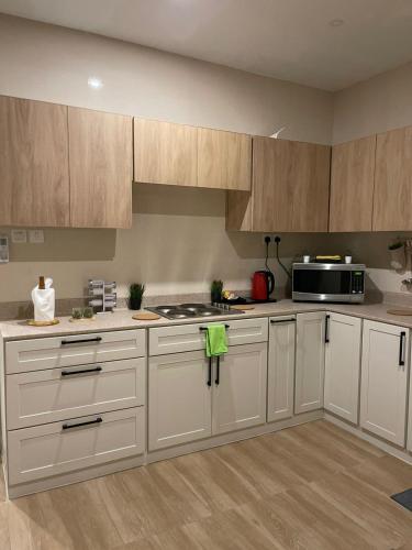 cocina con armarios blancos y microondas en Family Furnished Apartment in Khobar, en Al Khobar