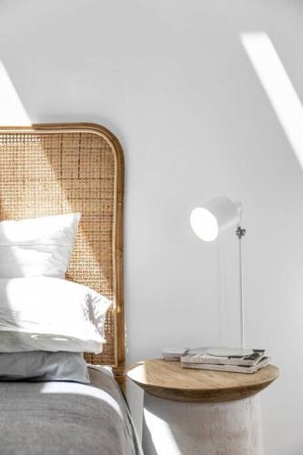 a bed with a rattan headboard and a table with books on it at THE OSLO on Broadway with Pool Villa 1 in Glenelg