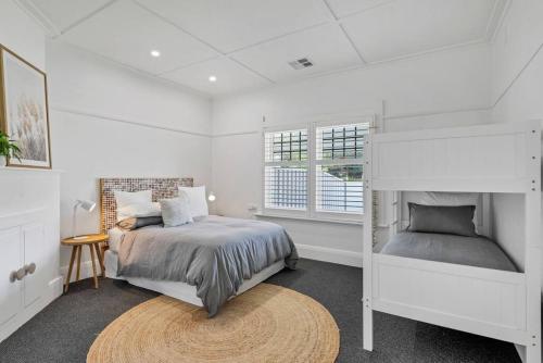 a white bedroom with a bed and a window at THE OSLO on Broadway with Pool Villas 1 & 2 in Glenelg