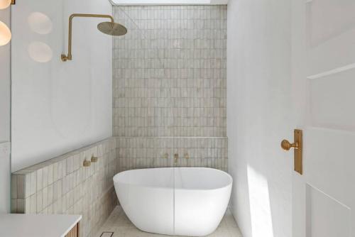 een badkamer met een groot wit bad en een wastafel bij THE OSLO on Broadway with Pool Villas 1 & 2 in Glenelg