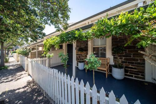 a house with a white picket fence and potted plants at Wisteria Cottage c1880 in Adelaide