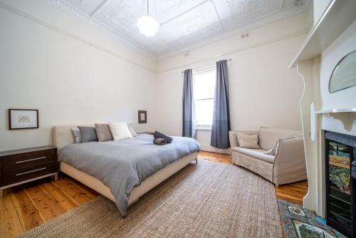 a white bedroom with a bed and a couch at The Oxford Hyde Park 4BR Cottage in Unley
