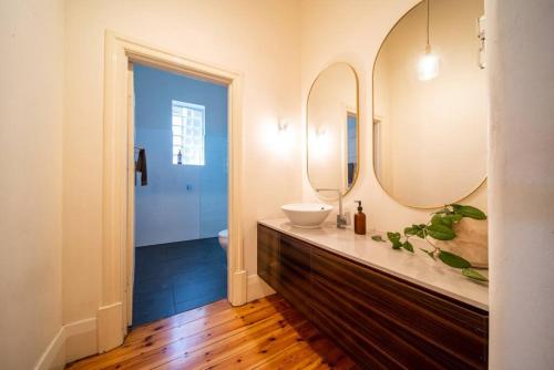 a bathroom with a sink and a mirror at The Oxford Hyde Park 4BR Cottage in Unley