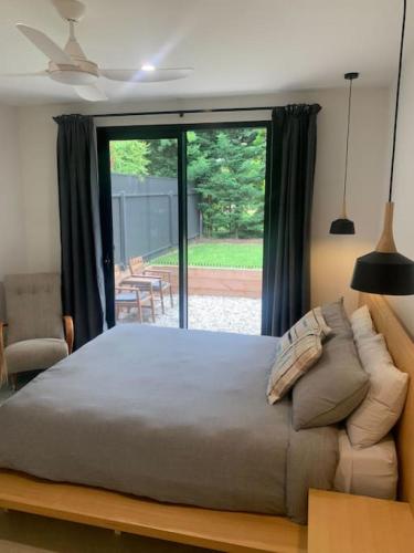 um quarto com uma cama grande e uma porta de vidro deslizante em The Architects House Villa 1 2BR em Hahndorf