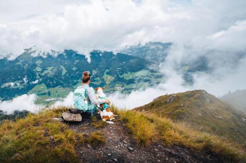 a man sitting on top of a mountain looking at the clouds at Ferienhaus Bergauf with Hot Tub in Neukirchen am Großvenediger