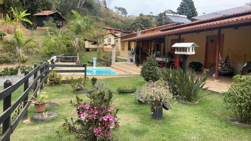ein Haus mit einem Garten mit Blumen und einem Zaun in der Unterkunft Sítio Olho de Boneca in Itamonte