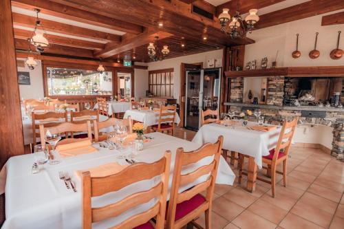 Relais Fleuri في Chermignon-dʼen Bas: مطعم بطاولات بيضاء وكراسي خشبية