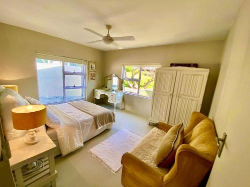 a bedroom with a bed and a chair and a window at Poolstraat 16 in Agulhas