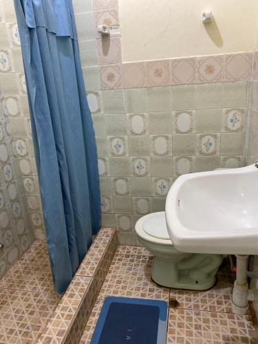 a bathroom with a toilet and a blue shower curtain at Casa Mafaldo in Iquitos