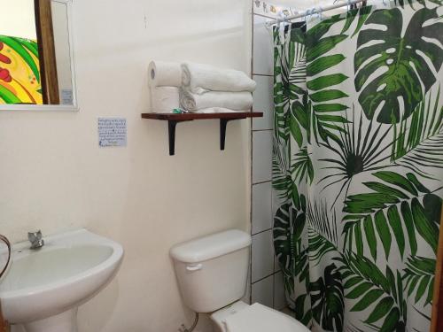ein Badezimmer mit einem WC, einem Waschbecken und einem Duschvorhang in der Unterkunft MisMiriam in Tortuguero