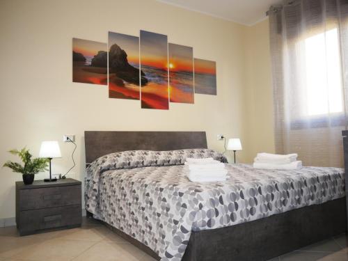 a bedroom with a bed with four paintings on the wall at Nicolo's Home in Quartu SantʼElena