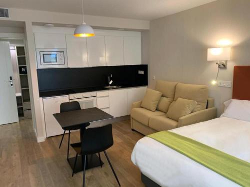 um quarto de hotel com uma cama, um sofá e uma mesa em Aparthotel Essenzia de Castilla em Aranda de Duero