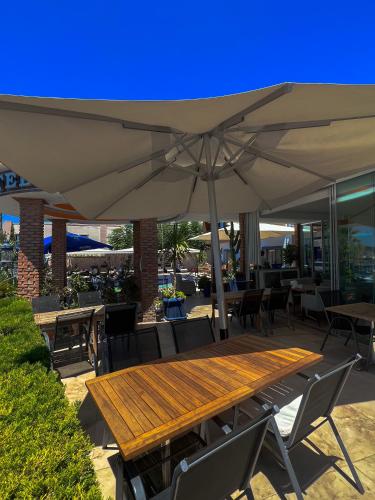a wooden table with an umbrella on a patio at Akkan Beach Hotel in Bodrum City