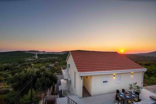 una pequeña casa blanca con la puesta de sol en el fondo en Sunset house, en Višnjevo