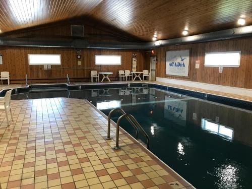 a swimming pool with chairs and tables at Acadia Village Resort in Ellsworth