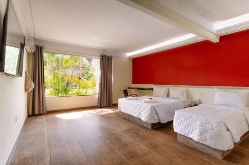 a bedroom with two beds and a red wall at Floral Inn Family in Porto Seguro