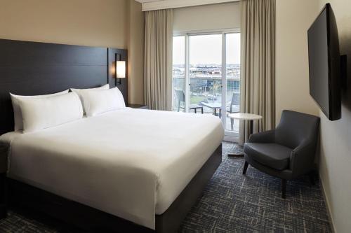a hotel room with a bed and a chair and a window at Residence Inn by Marriott Montreal Airport in Dorval