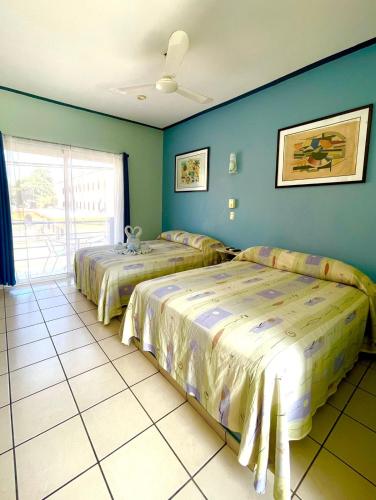 Duas camas num quarto com paredes azuis em Hotel Terraza Inn em Rincón de Guayabitos