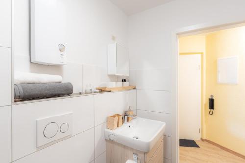 bagno bianco con lavandino e specchio di - Magical Harry Potter apartment in Duisburg - 2 Mins Central Station Hbf - Kingsize Bed & Netflix - a Duisburg